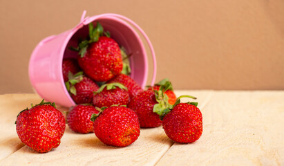 Strawberries in a pink bucket, scattered. Fresh strawberries on a wooden table. Strawberry juice. strawberries on a natural background.