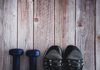 Dumbbells for fitness with trainers on wooden background. Gym accessories. Copy space. Selective focus.