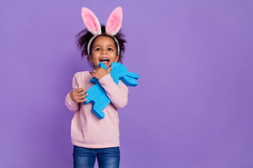 Portrait of attractive trendy cheerful sweet pre-teen girl holding bunny copy space isolated over bright purple violet color background