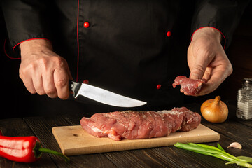 The chef cuts raw veal on a cutting board with a knife before cooking. Asian food. Hotel Recipe Idea