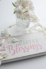 A delicate little bouquet of white alstroemeria flowers and a wooden plaque with the inscription in English "Easter Blessing". Spring Easter holiday.