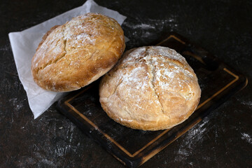 Fresh homemade crisp bread. Healthy baked bread on rustic cutting board over black wooden table.