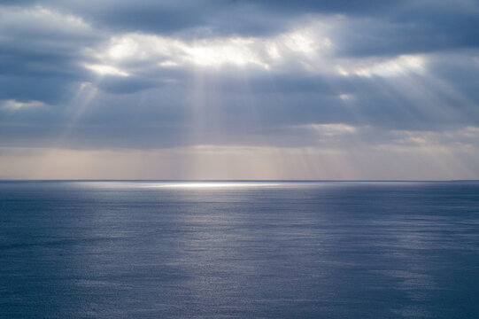 Sun rays through cloud cover on sea
