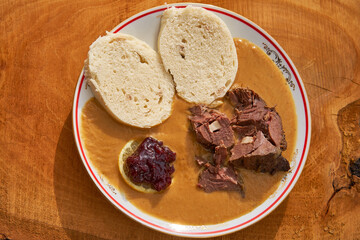 Top view on roasted fallow deer venison in sour cream sauce served with traditional czech bread...