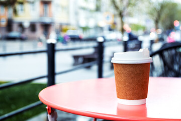 paper cup with coffee on the table. Rainy day in the city.