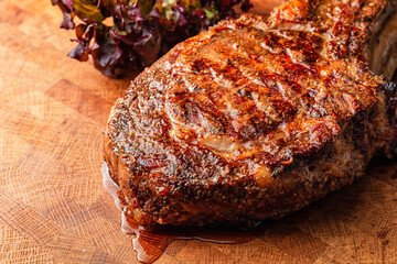 Juicy medium rare beef steak on wooden board with herbs.