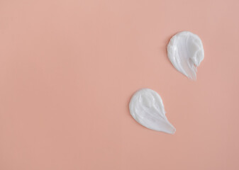 White smear of cosmetic cream on a beige background. Creamy foundation texture isolated. Smear of face cream. Close up of cream texture