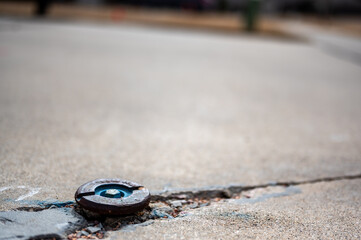 Water shutoff valve extending above a cracked concrete residential driveway. 