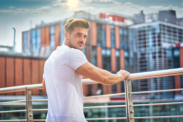 Fototapeta na wymiar Handsome young man in white t-shirt outdoor in city setting