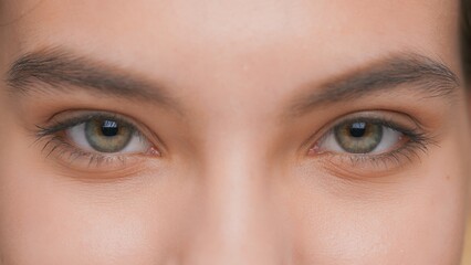 Extreme close-up of young woman opens her eyes and looks at camera, blinks and smiles