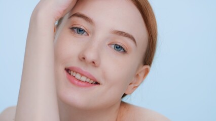 Obraz premium Young good-looking woman touches her skin sliding hand along a forearm, looks at camera and smiles