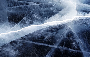 Transparent dark blue ice of frozen Baikal lake with white cracks pattern. Beautiful winter nature background.