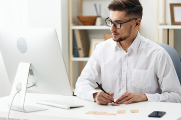 Fototapeta premium handsome businessman wearing glasses sits at a desk office worked technologies