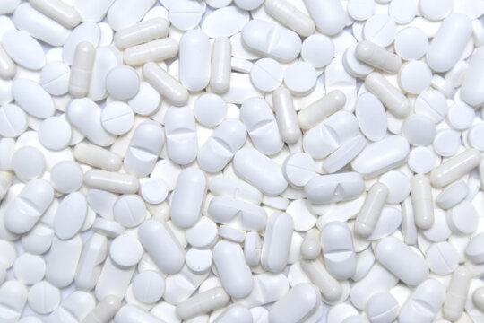 White pills, tablets and capsules background texture. Medicine and health care. © Lightly Stranded