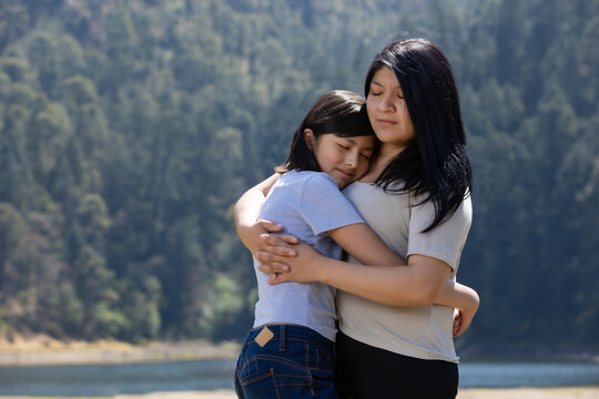 Mexican Mother And Daughter Hugging Outdoors, Women's Day