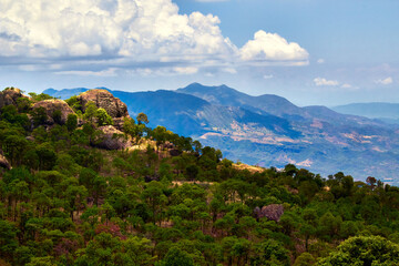montaña con roca en forma de perro con un bosque tropical y montañas en el fondo con grandes nubes blancas en la sierra de nanchititla, estado de México 
