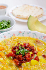Plate with tripe soup, called mondongo, traditional food from Colombia, South America, on light wood. Also called callos, guatita, tripa mishque, pancita, menudo.