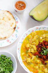 Plate with tripe soup, called mondongo, traditional food from Colombia, South America, on light wood. Also called callos, guatita, tripa mishque, pancita, menudo.