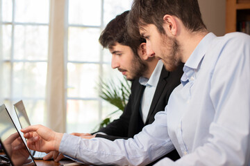 deux jeunes employés de bureau ou hommes d'affaires travaillent ensemble avec des ordinateurs portables.
