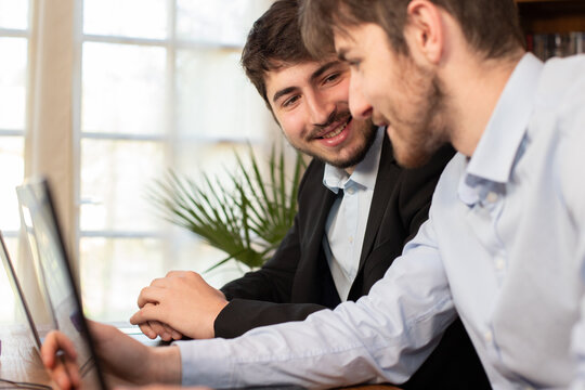deux jeunes coll&egrave;gues, employ&eacute;s de bureau ou hommes d'affaires se d&eacute;tendent et rient tous les deux en travaillant au bureau. Ils sont complices