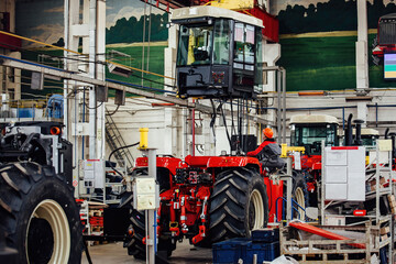 Industrial workers assembles agricultural tractor in workshop