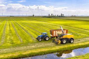 Fototapeta premium Tractors on fresh mowed green agricultural grassland