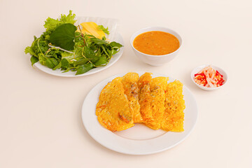Banh xeo, Vietnamese Crêpes or Pancakes with pork, shrimp, onions, beasn sprouts inside and fish sauce. Vietnamese food isolated on white background; perspective view