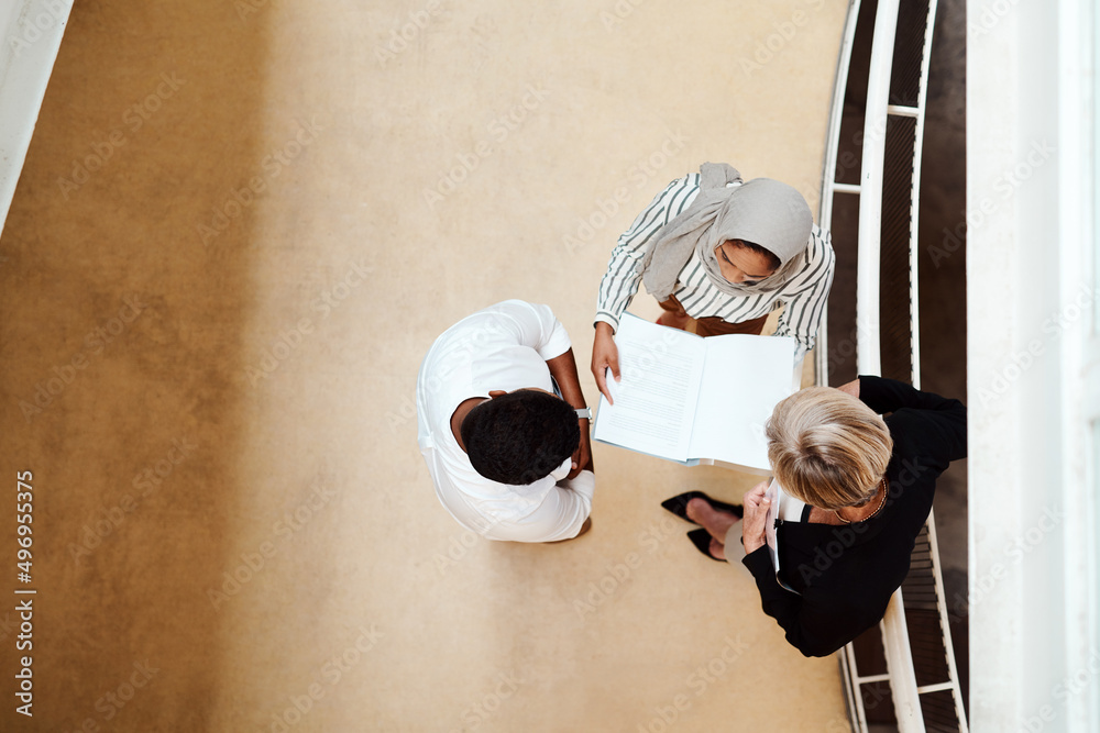 Poster Ensuring they remain on the same page. High angle shot of a group of businesspeople having a discussion while going through paperwork together in an office.