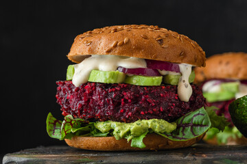 Veggie beet burgers with avocado, onion, mayonnaise and mixed salad on black background. Healthy...