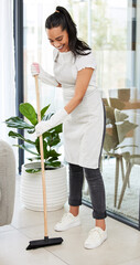 I make it a habit to clean my house on weekends. Full length shot of an attractive young woman standing and using a broom to sweep her home.