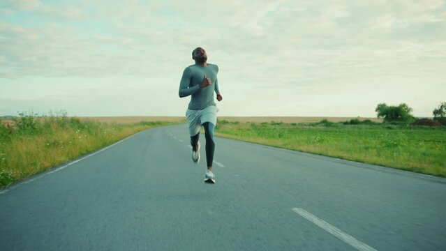Young athletic african american man running jogging on sunny road marathon sport healthy activity outdoors exercise slow motion