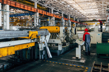 Workers and industrial machinery at metalworking factory production line
