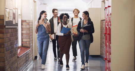 Keep learning, keep moving forward. Shot of a group of teenagers walking down the hall at high...