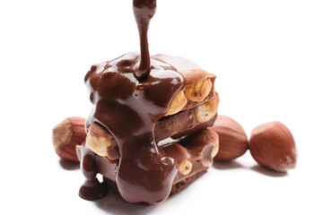 Pouring of liquid chocolate onto pieces with nuts on white background