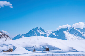 Fototapeta na wymiar Tracks on snow covered landscape slope against blue sky