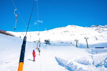 Fotobehang Skiers at drag lift on alps mountain against sky © ingusk