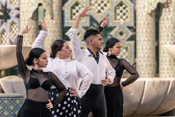 4 flamenco dancers lined up dancing and facing forward