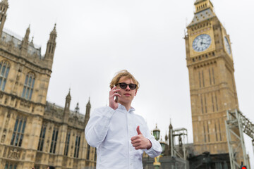 Young man, student talking on smart phone outdoor  near Westminster Bridge, London, England, near...