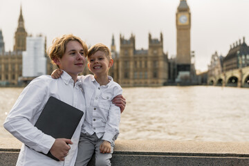 happy boys standing together over london with laptop