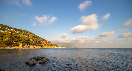 Naklejka premium Evening seascape with coastline illuminated by sunlight. View of the sea and part of the land.