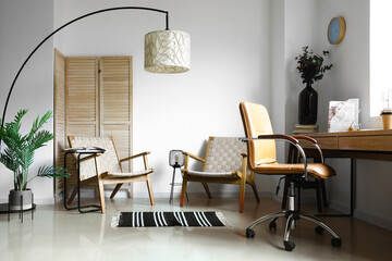 Interior of light room with armchairs, workplace and stylish floor lamp