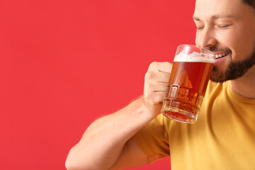 Handsome man drinking beer on red background