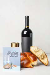 Traditional challah bread with greeting card and wine on white background. Shabbat Shalom