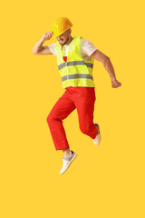Fototapeta na wymiar Young male worker jumping on yellow background