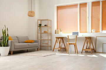 Interior of light room with modern workplace and sofa