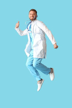 Young Male Doctor Jumping On Blue Background