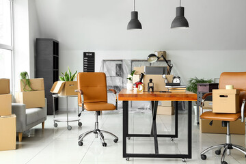 Cardboard boxes with belongings and furniture in interior of office on moving day