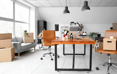 Cardboard boxes with belongings and furniture in interior of office on moving day
