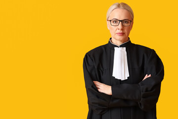 Mature female judge in robe on yellow background