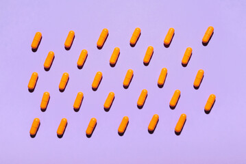 Turmeric powder capsules on purple background